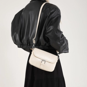 Sac bandoulière beige chic avec boucle argentée porté par un mannequin en studio