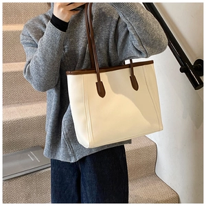 Detail of elegant cream tote bag with brown trim and long shoulder strap in daily use