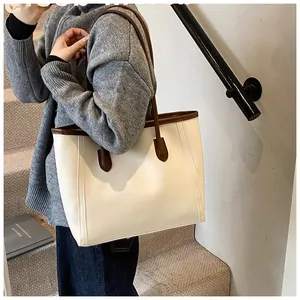 Detail of minimalist cream tote bag with brown handles and high-quality PU leather stitching