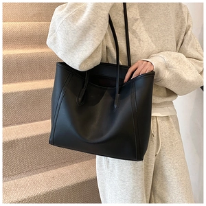 Macro shot of large black leather tote bag with vertical stitching for commuter style