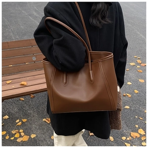 Detail view of a large dark brown faux leather tote bag with vertical stitching detail