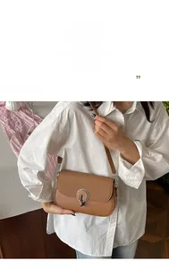 Detail of brown crossbody bag with circular metal buckle and woven leather texture