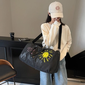 Large black canvas travel bag with colorful graffiti and leather handles shown by a model