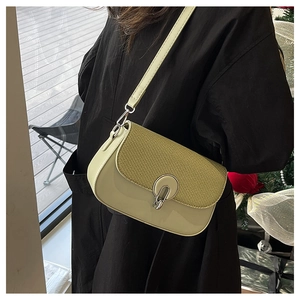 Detail of sage green crossbody bag with textured flap and silver oval metal clasp