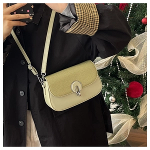 Detail of light green crossbody bag with textured flap and silver metal magnetic buckle