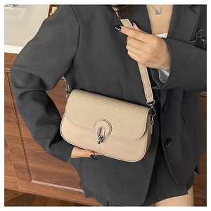 Detail of beige square bag featuring woven texture and silver metal buckle pendant