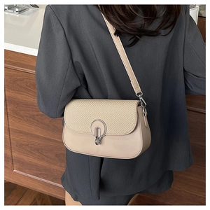 Detail of minimalist beige patchwork shoulder bag featuring straw texture and silver buckle