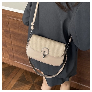 Detail of beige crossbody bag with geometric woven flap and silver ring buckle closure