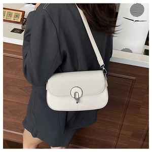 Close-up of white crossbody bag featuring woven texture and round silver metal buckle
