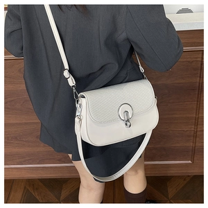 Detail of minimalist beige crossbody bag with woven texture and silver metal ring buckle