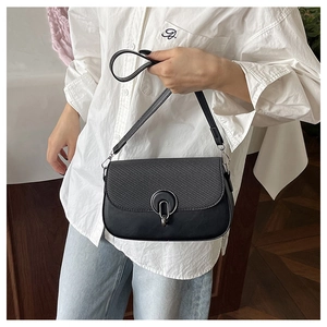 Detail of black leather square bag showing textured flap and silver metal ring buckle