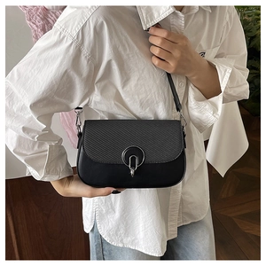 Close-up of black crossbody bag featuring textured flap and silver metal ring hardware
