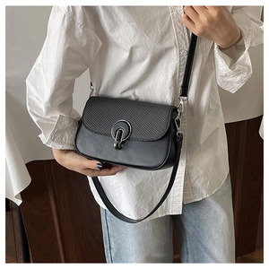 Detail of crossbody bag with woven texture, smooth leather, and silver ring clasp