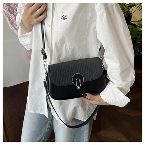 Detail view of black crossbody bag with faux snakeskin texture and silver ring buckle
