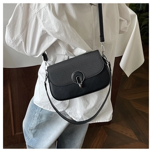 Detail of woven texture flap and silver metal buckle on black crossbody saddle bag
