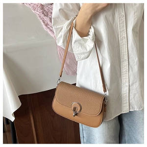 Detail of brown crossbody bag featuring woven texture flap and silver metal ring buckle
