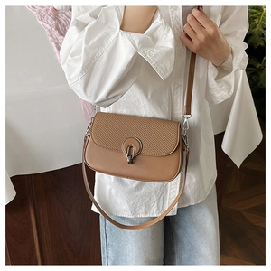 Detail of a brown crossbody bag with woven texture and a large silver metal ring buckle