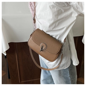 Detail of tan crossbody bag featuring woven texture flap and silver metal ring buckle