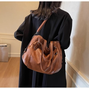Detail of caramel brown tote bag showing leather texture and silver metal buckles