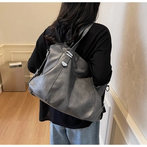 Detail of dark grey soft leather tote bag with metallic buckles and spacious interior