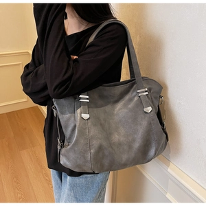 Close-up of a large dark grey textured leather tote bag with silver metal buckle details