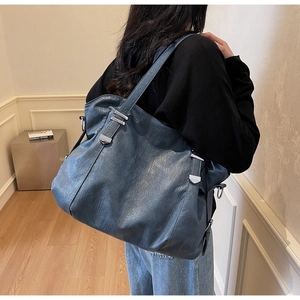 Detail view of large fog blue tote bag with pebble texture and silver buckle on shoulder