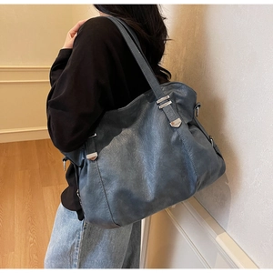Detail view of large dark grey-blue tote bag with adjustable strap on model