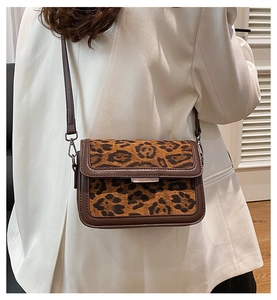 Detailed shot of leopard print shoulder bag on white blazer with adjustable brown strap