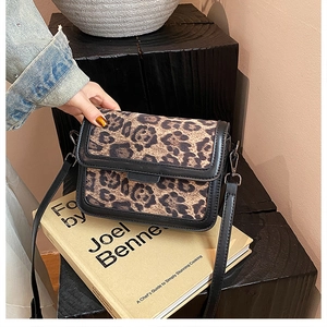 Close-up of leopard print crossbody bag featuring black leather trim and metal hardware