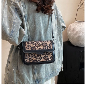 Detail shot of vintage leopard print crossbody bag on denim jacket from side view