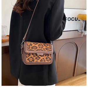 Side view of woman wearing a leopard print crossbody bag with metal accent and leather strap