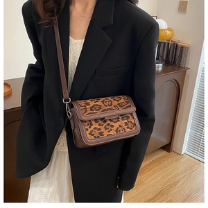 Detail of vintage leopard print crossbody bag with brown leather trim on a model