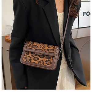 Detail of leopard print suede and dark brown faux leather crossbody bag on a model