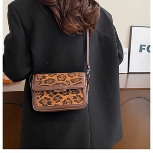 Lifestyle view of a vintage leopard print crossbody bag worn by a model in a cozy setting
