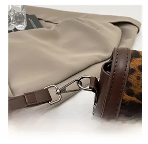 Detail view of the vintage silver metal hook and brown leather strap on a leopard print bag