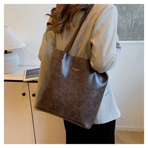 Borsa tote marrone in ecopelle indossata da una modella in ambiente interno