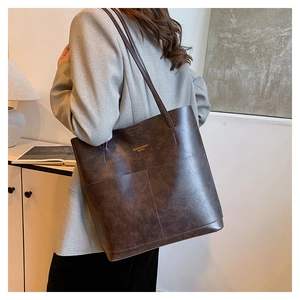 Dettaglio della grande borsa tote marrone con trama in pelle vintage e logo dorato