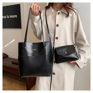 Dettaglio del set borsa tote in pelle nera minimalista e pochette con scritte dorate