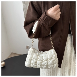 Close-up of white quilted bubble shoulder bag with a stylish gold chain strap