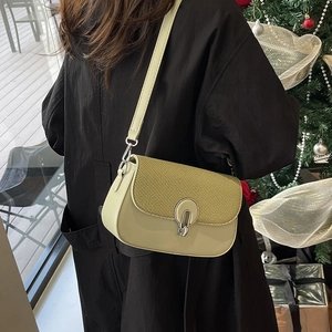 Pistachio green crossbody bag with textured flap and silver oval buckle on holiday background