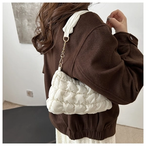 Detail of white quilted cloud shoulder bag with chain strap and ruched fabric texture