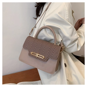 Detail of vintage crossbody bag featuring beige leather and brown herringbone stitching