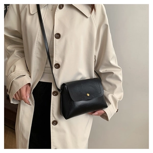 Detail of black wax leather crossbody bag with a gold buckle on a stylish model