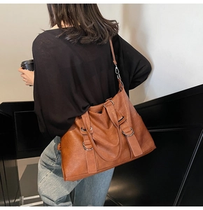 Détail latéral d'un grand sac cabas marron caramel avec boucles métalliques argentées
