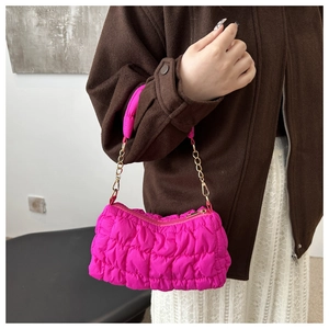 Close-up of pink quilted bubble bag with metallic gold chain and puffer texture detail