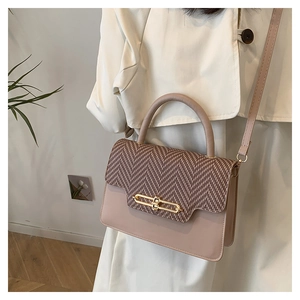 Detail of pink faux leather bag featuring herringbone fabric flap and gold clasp