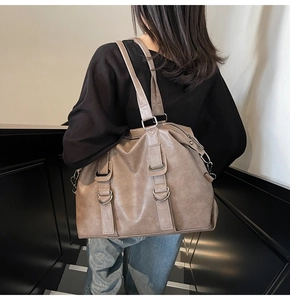 Détail d'un grand cabas vintage en cuir marron porté à l'épaule par un mannequin