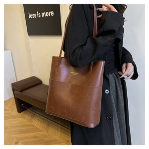 Dettaglio di una borsa tote grande in pelle sintetica marrone vintage con manici e tasca
