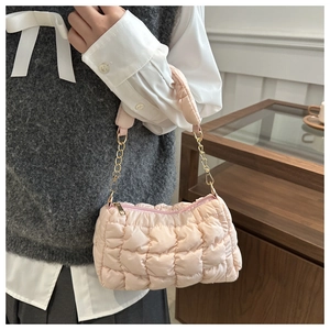 Close-up of light pink quilted cloud bag with gold chain strap and soft padded texture