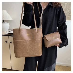 Detailed view of brown leather tote bag with small matching pouch and gold SENDIOMHU logo